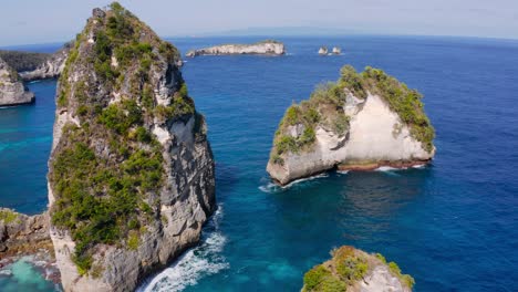 Beautiful-tilting-shot-of-huge-rock-formations-called-Nusa-Penida-Thousand-Islands-on-a-sunny-summer-day