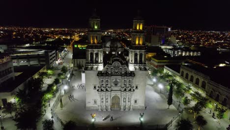 Aerial-view-away-from-the-illuminated-Metropolitan-Cathedral-of-Chihuahua---Pull-back,-drone-shot