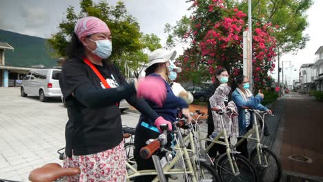 5-Asiatische-Frauen,-Die-Gesichtsmasken-Tragen-Und-Auf-Fahrrädern-Sitzen-Und-Einen-Daumen-Hoch-Für-Die-Kamera-Machen