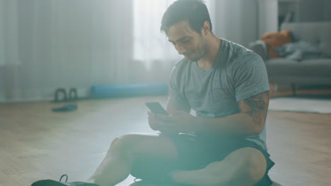 Fitness-man-taking-a-break-from-his-work-out-and-he-is-reading-the-messages-on-his-phone