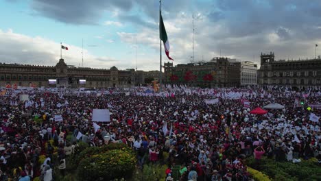 Zocalo-Square-flag-waving-at-a-crowd-gathering,-protest-in-Mexico-city---Aerial-view
