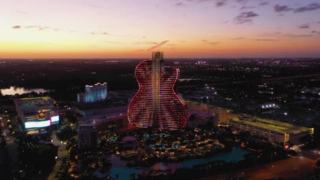 Seminole-Hard-Rock-Hotel,-illuminated-with-beautiful-night-colors-during-dusk---Aerial-view