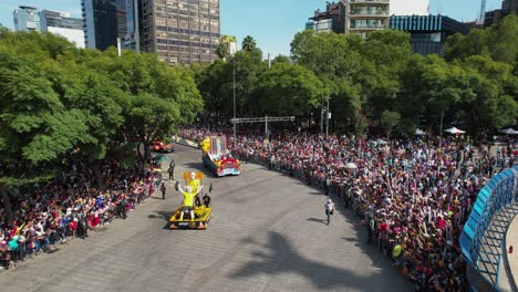 People-watching-a-convoy-of-decorated-trucks-at-the-Day-of-the-dead-parade,-in-sunny-Mexico-city---aerial-view