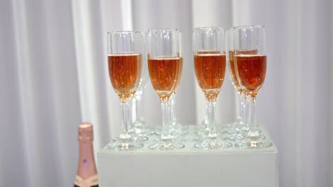 Gläser-Mit-Prickelndem-Champagner,-Die-Symmetrisch-Auf-Einem-Weißen-Ständer-Neben-Der-Flasche-Ausgestellt-Sind