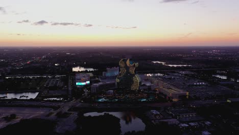 Aerial-view-towards-the-illuminated-Seminole-Hard-Rock-Hotel-and-Casino-Hollywood,-dusk-in-Florida,-USA---approaching,-drone-shot