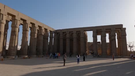 Panning-shot-of-the-large-columns-and-tourists-admiring-the-Luxor-temple