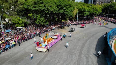 Aerial-view-of-decorated-wagons-and-horses-at-the-Dia-de-Muertos-Parade,-in-sunny-Mexico-city