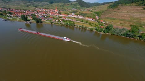 Amazing-FPV-Shot-Flying-Low-Close-To-Transport-Ship-Cruicing-Danube-River,-Weissenkirchen,-Austria