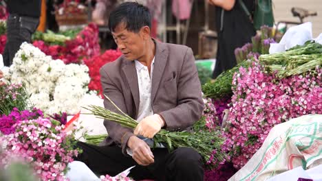 Kunming,-Yunnan,-China---September-1,-2022:-old-man-florist-busy-tidying-up-their-flowers-at-the-Kunming-Dounan-Flower-Market