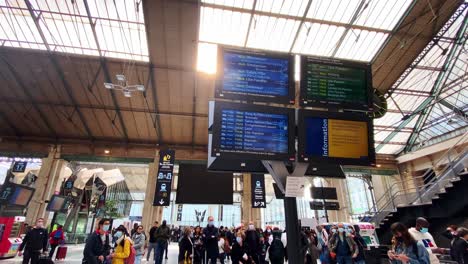 Pantalla-De-Visualización-De-Horarios-En-La-Estación-De-Tránsito-Gare-Du-Nord-Con-Pasajeros-En-París,-Francia
