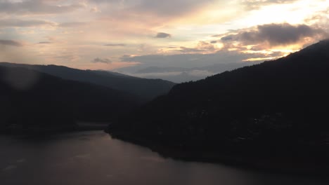 Luftaufnahme-Des-Sonnenuntergangs-über-Einem-Hügel-Mit-Einem-Atemberaubenden-See-Im-Vordergrund