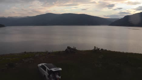 Drone-view-of-a-stunning,-serene-lake-in-North-Macedonia-with-a-beautiful-sunset-in-the-background