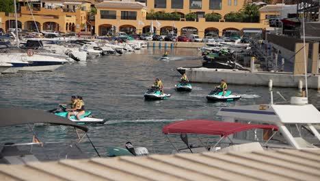 Group-of-People-on-jetskis-passing-by-in-the-marina-surrounded-by-yachts