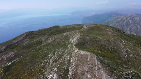 Aerial-push-out-of-tall-rocky-mountains-by-sea,-Galičica-National-Park