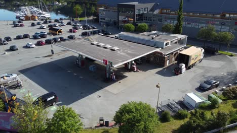 YX-fuel-and-energy-station-with-7-eleven-kiosk-in-Arna-outside-Bergen-Norway---Aerial-loking-down-at-building-with-delivery-truck-outside-and-ev-cars-charging-batteries-to-the-left