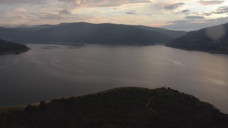 Bird's-eye-view-of-a-calm-lake-in-North-Macedonia-with-a-beautiful-sunset-in-the-background