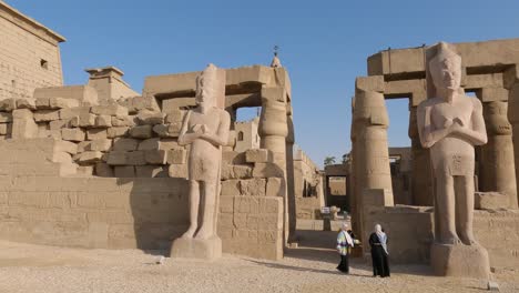Group-of-women-tourists-visiting-two-stone-carved-statues-at-Luxor-Temple,-Egypt