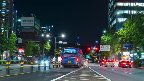 N-Seoul-Namsan-Tower-Blick-Von-Der-Belebten-Straße-In-Der-Innenstadt-Von-Seoul-City-Bei-Nacht-Mit-Sich-Schnell-Bewegendem-Verkehr,-Zeitraffer,-Wechselnde-Ampeln,-Neonlichtpfade---Schwenkbewegung