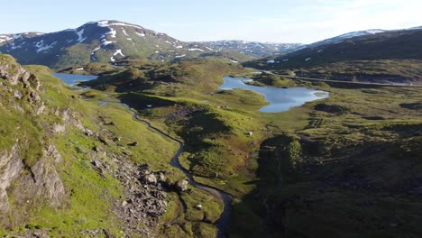 Friends-out-tenting-in-wonderful-pristine-landscape-at-Vikafjellet-mountain-Norway---Summer-aerial-following-small-river-and-passing-three-tents-to-the-right