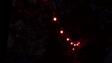 Schwenkaufnahme-Von-Sehr-Schwachen-Roten-Glühbirnen,-Die-Hängen-Und-Eine-Düstere-Atmosphäre-Schaffen