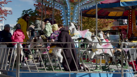 Static-slow-motion-shot-of-a-mother-and-kids-having-fun-on-horses-in-a-merry-go-round