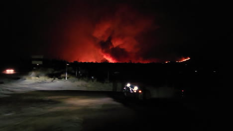 Vierradfahrzeug-Bei-Nacht,-Das-Sich-Auf-Der-Landstraße-Mit-Wildfire-Flammen-Im-Hintergrund-Bewegt,-Fairview,-Kalifornien,-USA