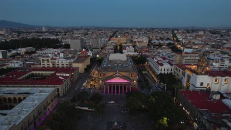 Aerial-view-away-from-the-illuminated-Teatro-Degollado,-evening-in-Guadalajara,-Mexico---pull-back,-drone-shot