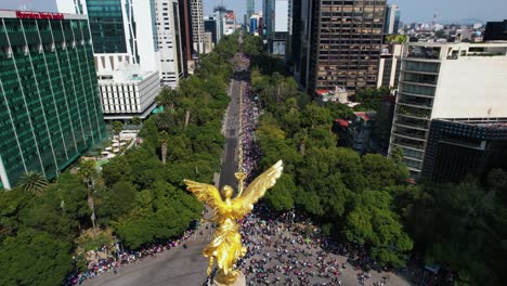 Vista-Aérea-Sobre-La-Estatua-Del-Ángel-De-La-Independencia,-Desfile-En-La-Avenida-Reforma,-Ciudad-De-México