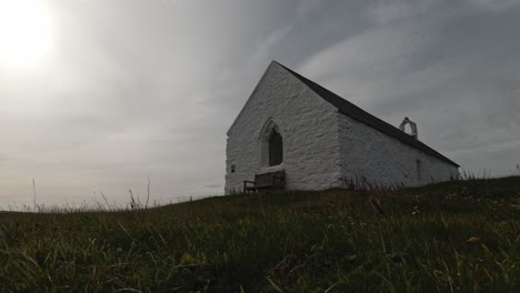 Tourists-walking-dog-at-old-St-Cwyfan-white-church-on-windy-Anglesey-coast