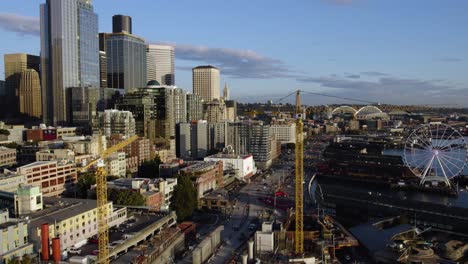 Aerial-view-of-a-road-construction-site-at-the-central-waterfront-of-Seattle-city,-golden-hour,-in-Northwest-USA---reverse,-drone-shot