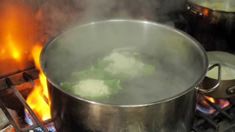 Throwing-cauliflower-head-to-pot-with-boiling-water,-close-up