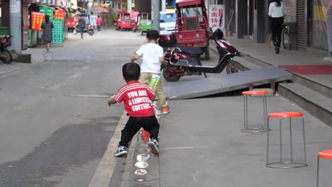 two-boys-walk-over-puddles-at-the-Dounan-Flower-Market-complex-in-Kunming,-Yunnan,-China-on-September-1,-2022