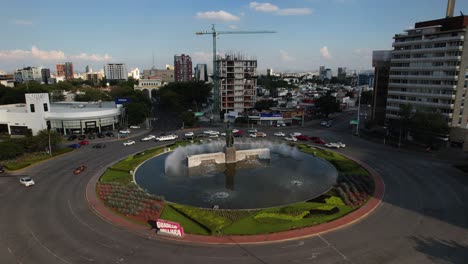 Aerial-view-around-car-driving-around-the-Minerva-traffic-circle,-in-Guadalajara,-Mexico---orbit,-drone-shot