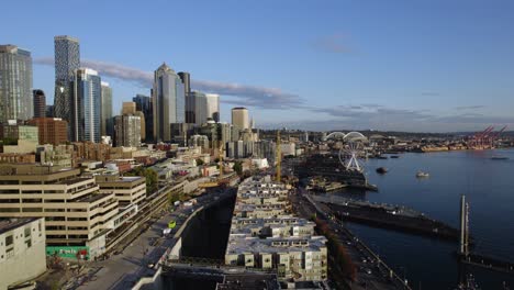 Aerial-view-over-the-Central-Waterfront-of-Seattle,,-golden-hour,-in-Washington,-United-States-of-America---reverse,-drone-shot