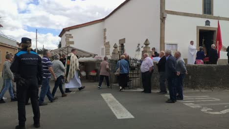Catholic-religious-people-entered-the-church-in-procession-celebrating-the-day-of-the-saint-under-the-control-of-the-police,-cloudy-day,-blocked-shot,-Poulo,-A-Coruña,-Galicia,-Spain