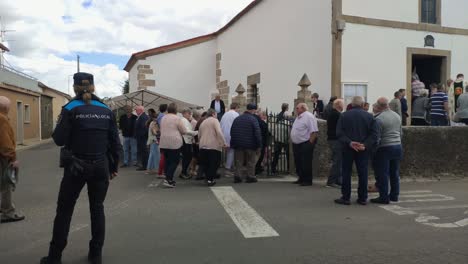 Katholische-Religiöse-Menschen-Betraten-Die-Kirche-In-Einer-Prozession,-Die-Den-Tag-Des-Heiligen-Unter-Der-Kontrolle-Der-Polizei-Feierte,-Bewölkter-Tag,-Blockierter-Schuss,-Poulo,-A-Coruña,-Galizien,-Spanien