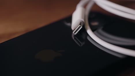 Rack-Fokus-Des-USB-C-Kabels-Aufgerollt-Auf-Der-Rückseite-Eines-Apple-IPhone-Smartphones-Auf-Dem-Schreibtisch