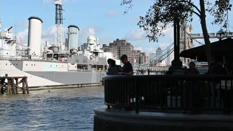 People-Standing-In-Front-of-HMS-Belfast-and-Tower-Bridge,-Canary-Wharf,-London,-United-Kingdom