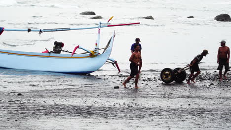 Typical-Indonesian-canoe-at-rest,-fishermen-leaving-with-cart