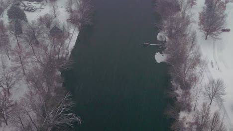 Top-down-aerial-view-of-a-river-with-snow-on-both-sides