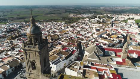 Aerial-panning-shot-from-the-church-of-santa-maria-to-the-old-town-medina-sidonia-in-spain-with-mainly-white-buildings-on-a-beautiful-sunny-day