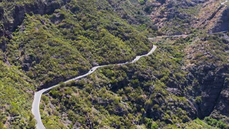 Scenic-mountain-pass-road-along-steep-slope-during-sunny-day,-aerial