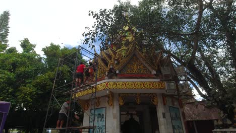 People-repairing-roof-of-Thai-Temple,-handheld-view
