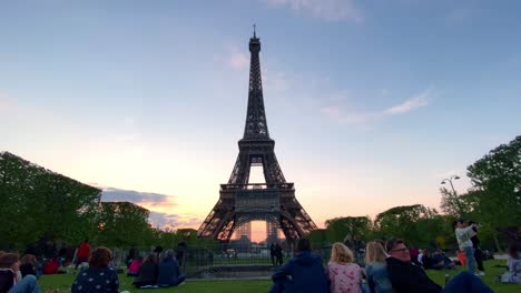 Leute-Hängen-Am-Champ-De-Mars-Mit-Dem-Eiffelturm-Im-Hintergrund-In-Der-Abenddämmerung-In-Paris,-Frankreich-Ab