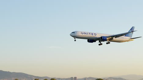 Slow-motion-United-airlines-passenger-jet-flying-across-Barcelona-skyline-on-approach-to-airfield