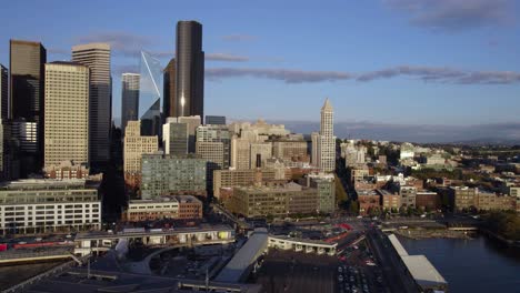 Aerial-view-low-in-front-of-the-Central-Waterfront-skyline-of-Seattle,-sunrise-in-the-Pacific-Nortwest-of-USA