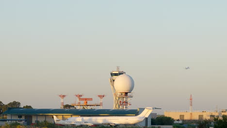 Sunrise-view-over-Barcelona-airport-control-tower-with-air-plane-takeoff-across-background-skyline