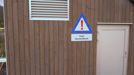 Sign-warning-about-hydroelectric-powerplant-on-wall-of-Markaani-powerplant-in-Vaksdal-Norway
