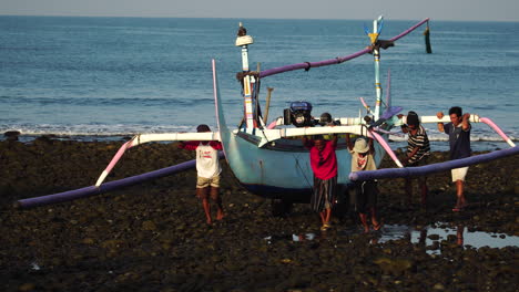 Scene-of-fishermen-carrying-typical-Indonesian-outrigger-canoe-out-of-sea