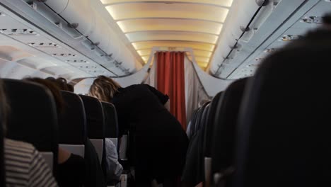 Air-hostess-checking-passenger-seat-belts-before-takeoff